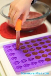 My son transferring the warm liquid to the fruit snack molds