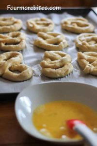 Brushing egg on boiled homemade soft pretzel dough