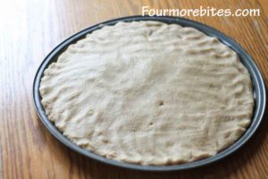 Lemon sugar cookie dough spread out on pizza pan.