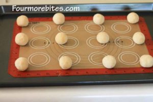 Lemon sugar cookie dough balls on a cookie sheet lined with silpat silicone mate