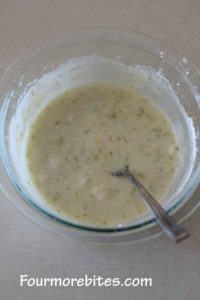 Lime glaze for lime sugar cookies in a clear bowl on a white counter top.