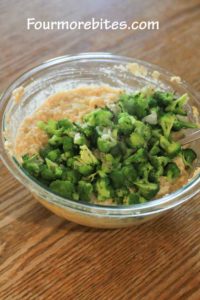 Broccoli added to rice and cheese mixture in a glass pyrex bowl sittng on an oak table