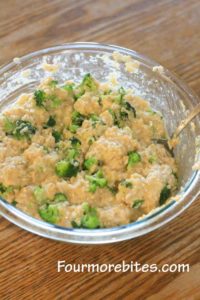 Broccoli and rice and cheese mixture thoroughly mixed in a glass pyrex bowl siting on an oak table