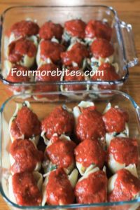 Stuffed shells toped with marinara sauce in two 8x8 glass pans.