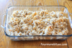 Turkey and cheese in a pyrex glass casserole dish sitting on a wood table