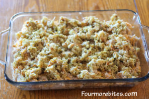 Turkey, cheese and stuffing in a pyrex glass casserole dish sitting on wood table. This casserole is ready to go in the oven.